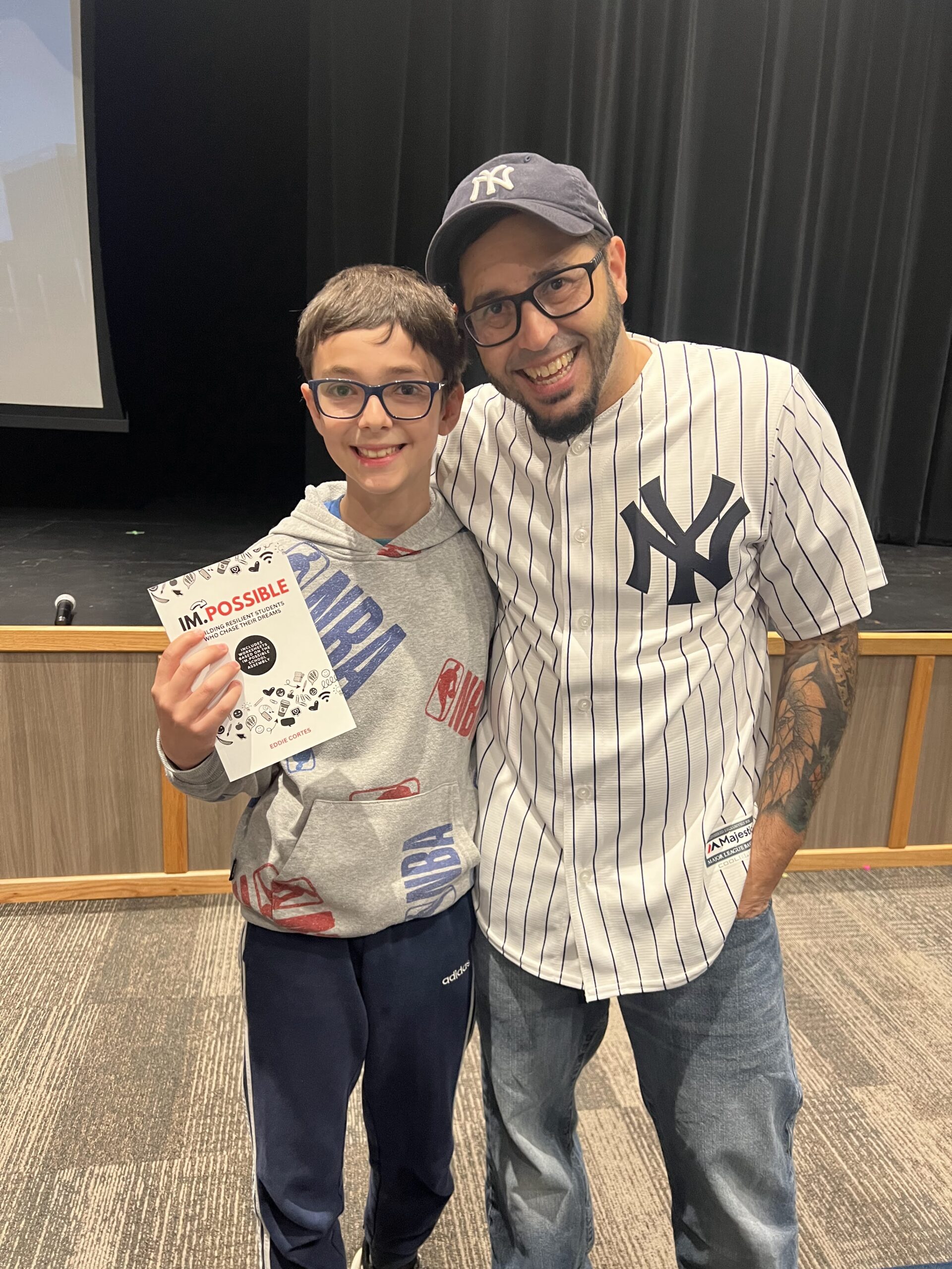 IM.POSSIBLE Book by Author and Motivational Youth Speaker Eddie Cortes at a School Assembly Program with  and student 